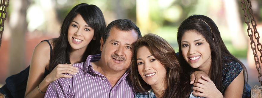 Family of four smiling on front porch swing