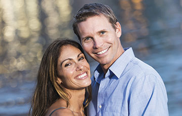 Couple in front of lake smiling at camera
