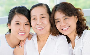 Three multi-generational women smiling and leaning into each other