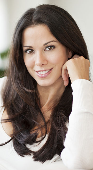 Brunette with long hair smiling with head on her hand