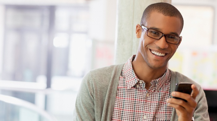 young man in glasses holding phone smiling