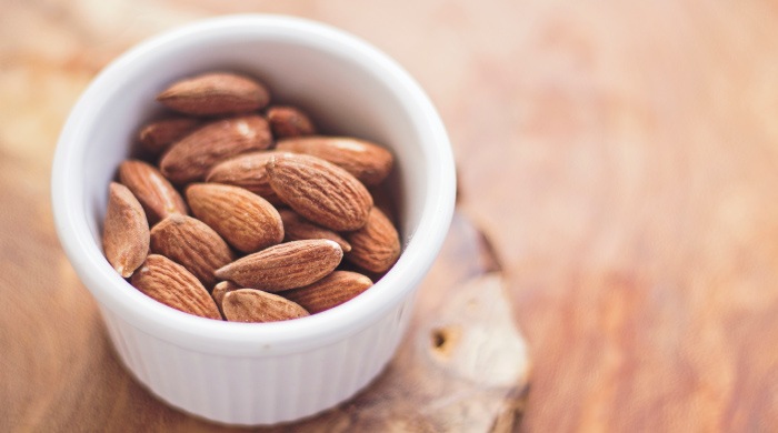 Aerial view of a white custard cup of calcium-rich brown almonds