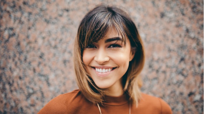 browned haired girl wearing a rust shirt and a big toothy smile