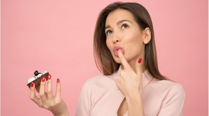 woman holding a donut licking frosting off her finger