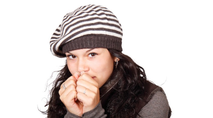 girl wearing a beret huddled up against the cold