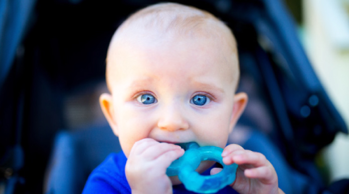 blue eyed baby boy teething on a blue toy