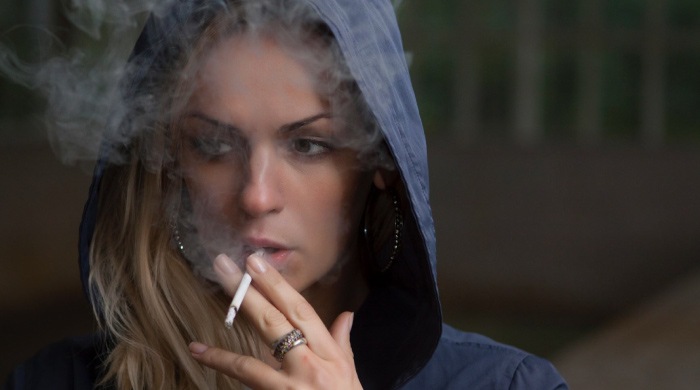 woman in a hoodie smoking a cigarette