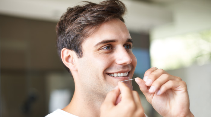 man flossing his teeth to prevent plaque buildup