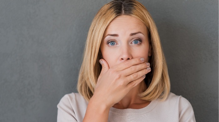 blond woman covering her mouth with acid erosion on her teeth