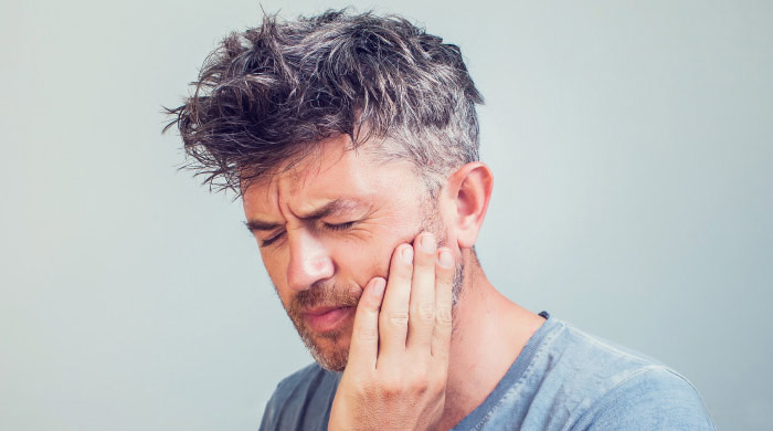 man holding his jaw and grimacing in pain