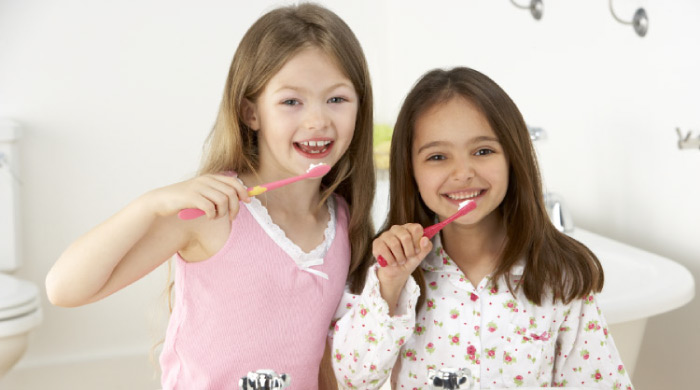two young girls brushing their teeth together