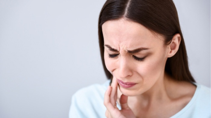 woman holding her jaw with painful gums