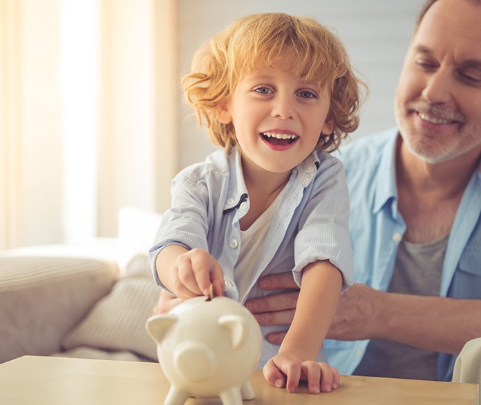 kid putting coin in piggy bank