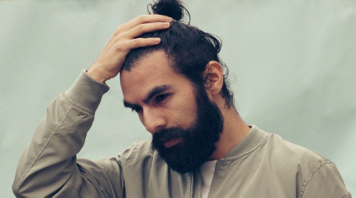 bearded man holds his head with a headache from night time teeth grinding