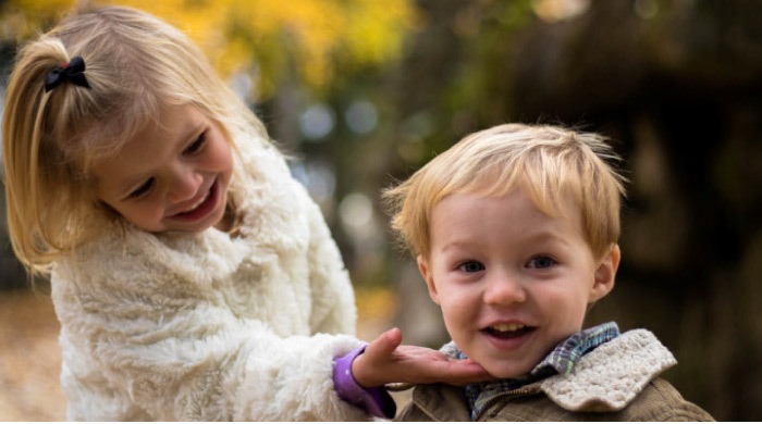 young girl shows off her baby brothers toothy smile