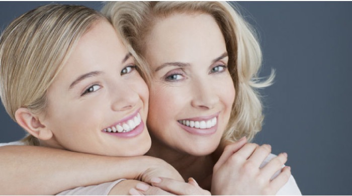 two blond women smile and hug after learning about professional teeth whitening