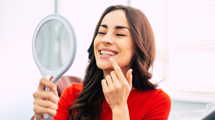 woman looking in a mirror at her teeth