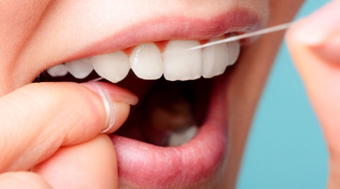 closeup of a woman flossing her teeth