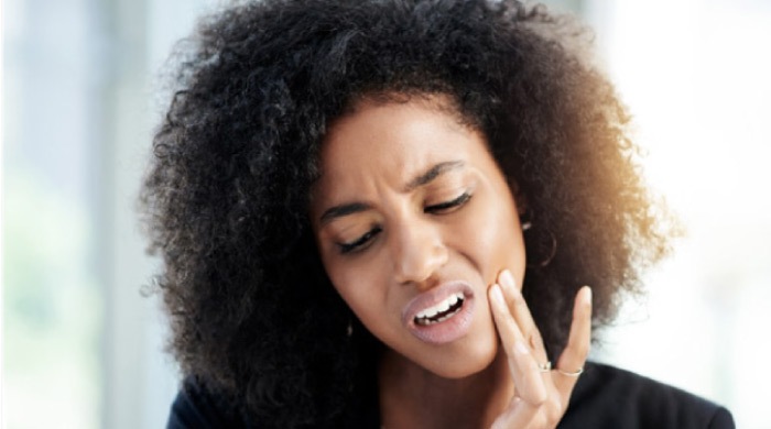 woman holding her jaw in pain needs a root canal