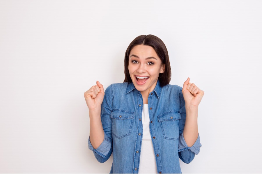 young woman shows her excitement about same day CEREC crowns at the dentist office