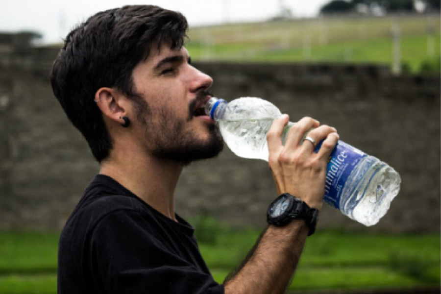 young man drinking a big bottle of water