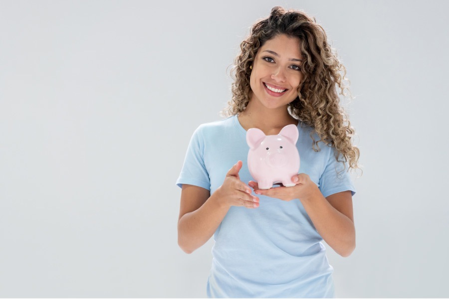 woman holding a piggybank and smiling about affordable dentistry