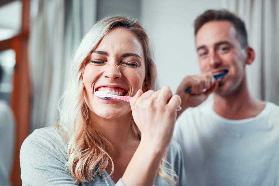 a couple brush their teeth together to prevent dental decay