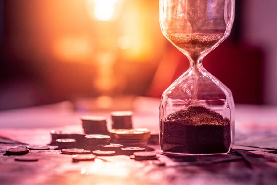 small stacks of coins next to an hourglass coursing with sand