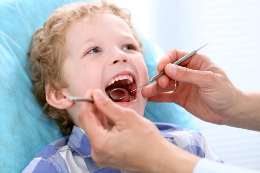 young boy with his mouth open getting a dental exam