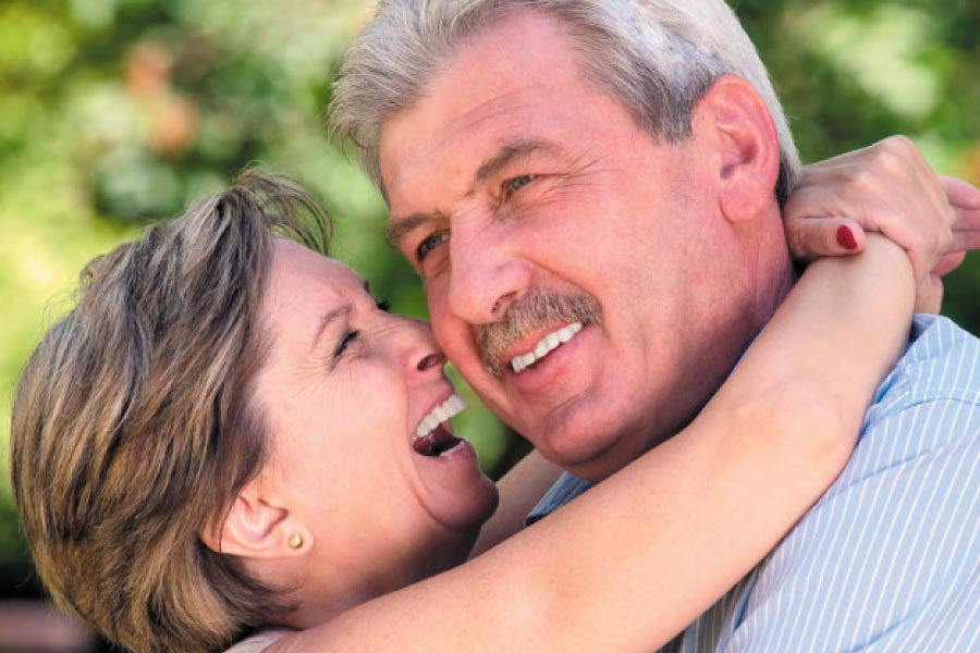 senior couple hug and smile after learning how versatile dental implants are