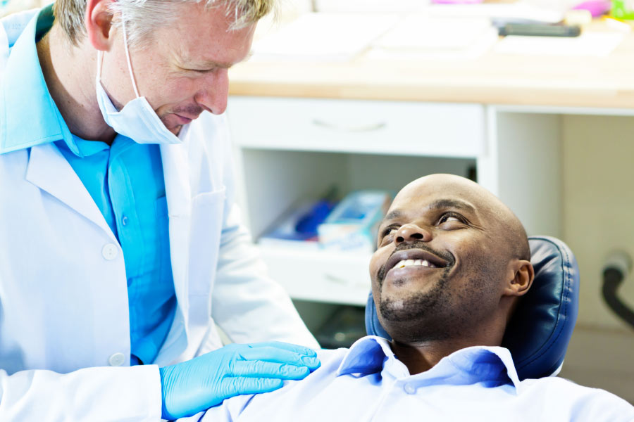 male dental patient sits in the dentist chair and talks with the dentist about his new dental implant