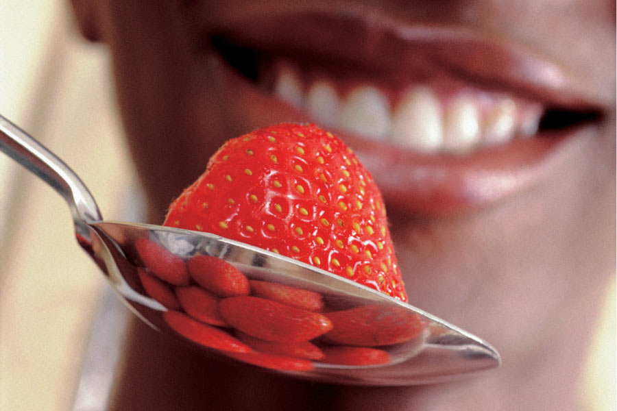 close up of a strawberry in a spoon about to be eaten
