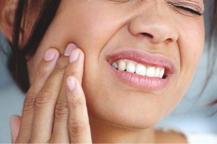 woman holds her cheek in pain with a root canal infection