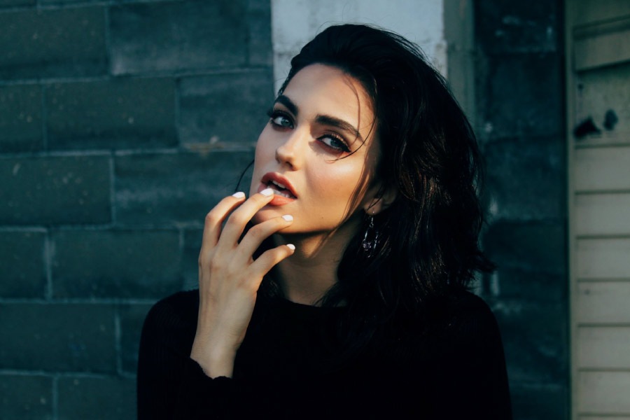 dark haired young woman checks her mouth for a cracked tooth